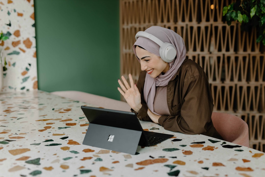 Woman in a hijab in a modern apartment kitchen, looking thoughtfully out the window.