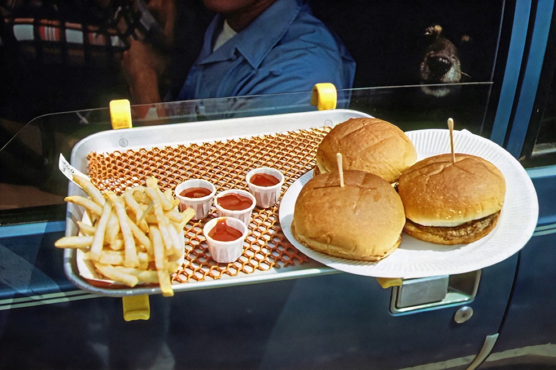 Hand reaching for a burger on a table filled with fast food