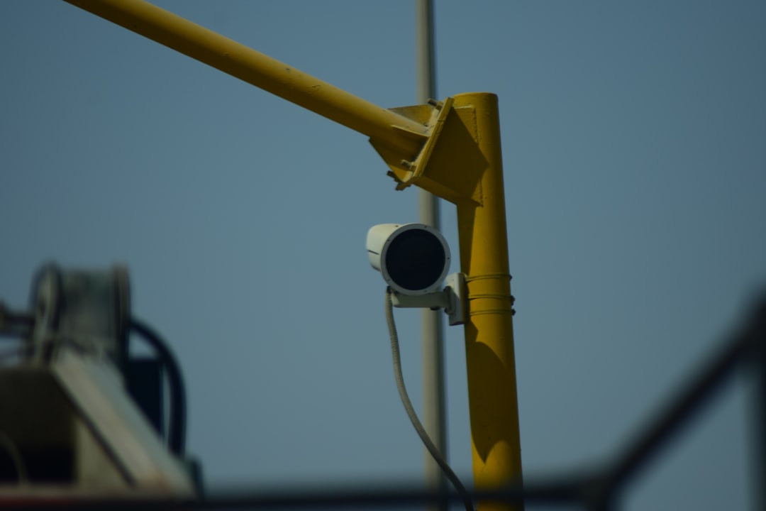 surveillance camera on a pole with barbed wire in background