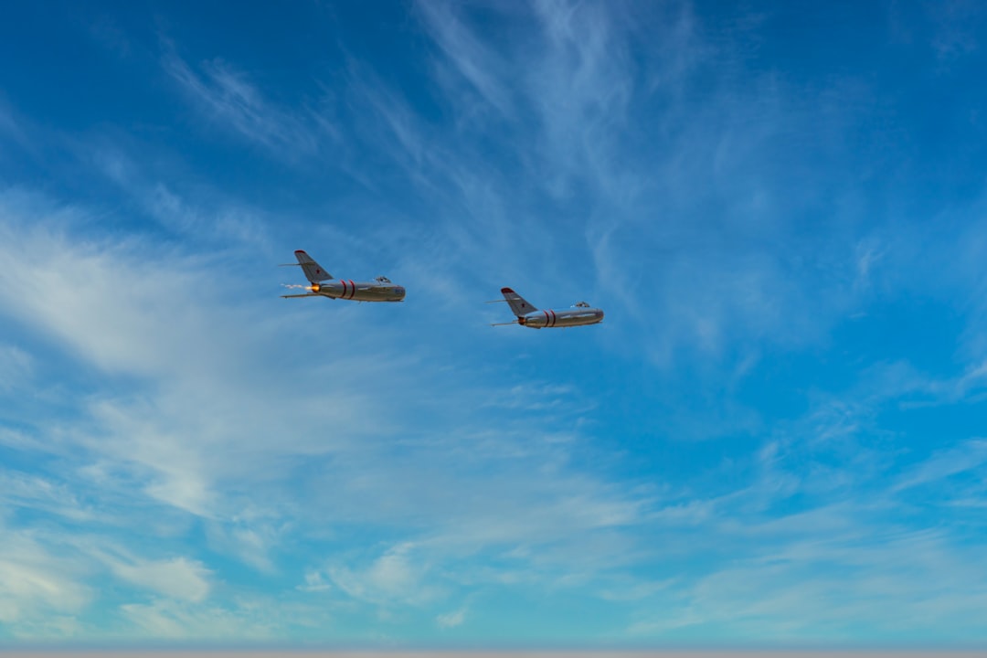 Two Japanese F-15 fighter jets flying in formation against a clear blue sky above the ocean.