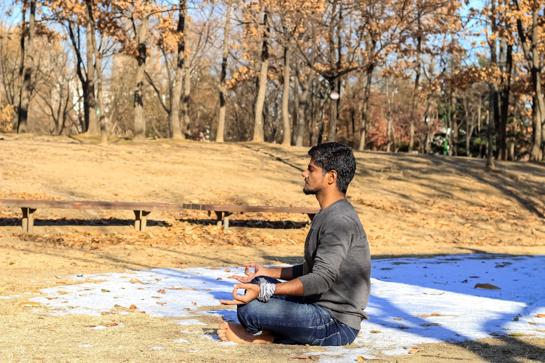 Man practicing yoga outdoors. Emphasizes the importance of regular exercise and connecting with nature.